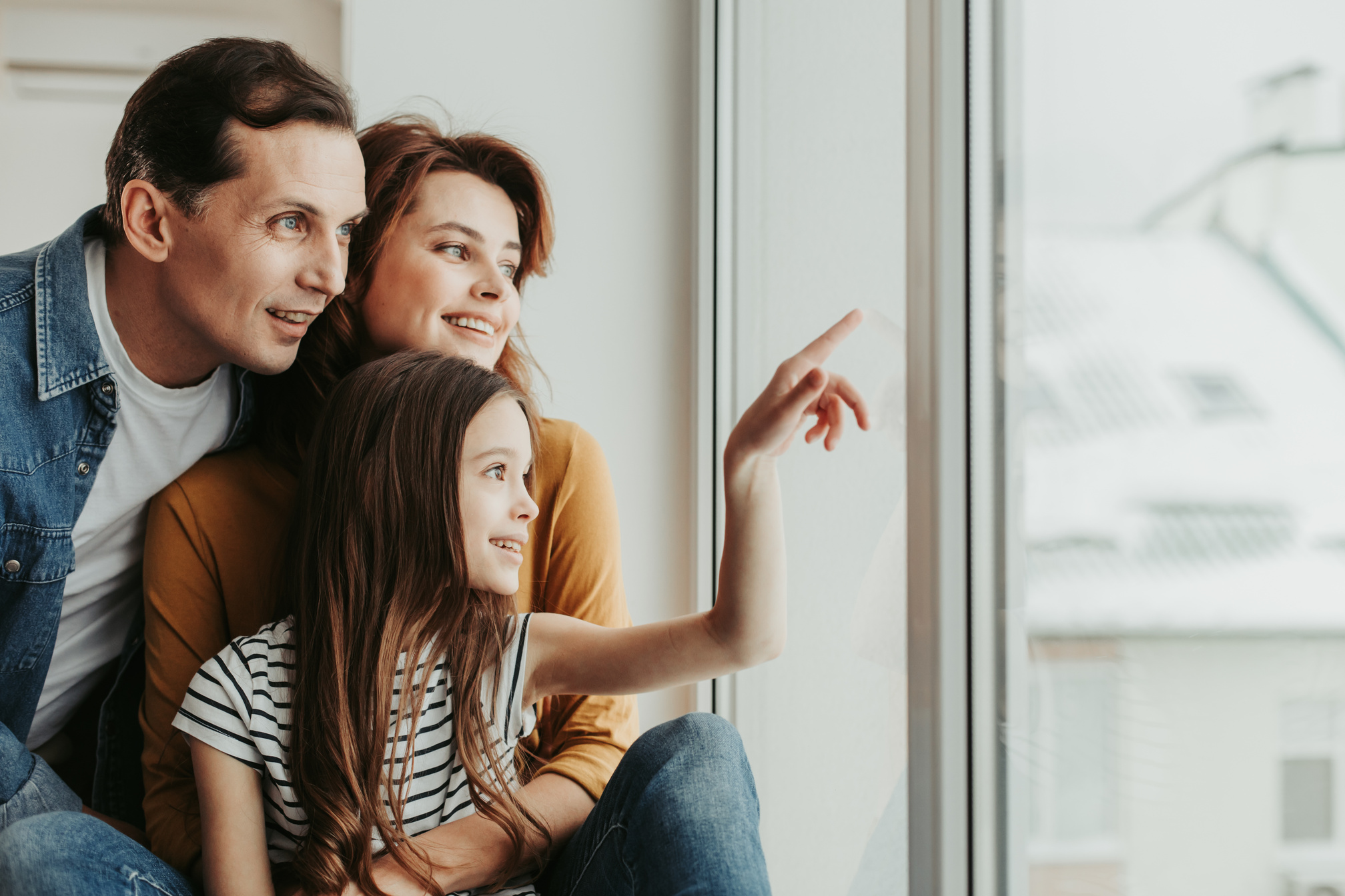 Happy family curiously looking at home window